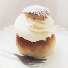 En semmeltårta med fluffig grädde och pudersocker, redo att avnjutas. Ett perfekt semmeltårta recept för fika.