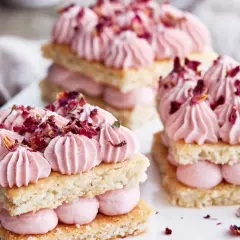 Delikata små mandelbotten tårtor med rosa grädde och torkade rosenblad. En dröm för ögat och gommen.