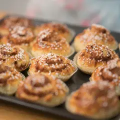 Nybakade glutenfria bullar med pärlsocker på en plåt, redo att avnjutas.