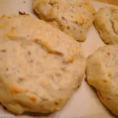 Nybakade bullar med bakpulver, fulla av frön, ligger på ett bakplåtspapper.