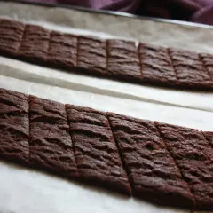 Två långa rader med nybakade chokladsnittar på bakplåtspapper. Perfekt för ett chokladsnittar recept.