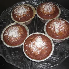 Fem kladdkakemuffins med kola och kokosflingor på ett glasfat.