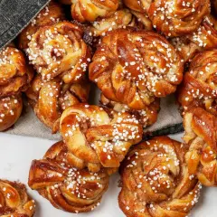 En hög med gyllene snurra bullar, toppade med pärlsocker. Doften av kanel sprider sig från dessa nybakade godsaker.