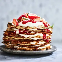En imponerande pannkakstårta med grädde och jordgubbar, perfekt för ett somrigt pannkakstårta recept.