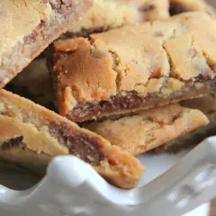 Nära bild på gyllene dumle snittar med chokladbitar, staplade i en vit skål. Perfekt för fikat!