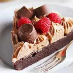 En bit kladdkaka med fluffig chokladfrosting, toppad med hallon och chokladbitar. En perfekt kombination för alla chokladälskare.
