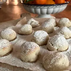 Små, pudrade bakverk som påminner om torta caprese, ligger utspridda på bakplåtspapper.