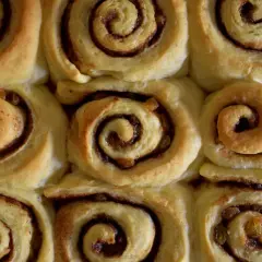 Nybakade kanelbullar med russin, redo att avnjutas. Doften av kanel sprider sig i köket.