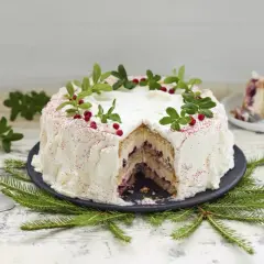En vacker tårta med grädde, lingon och gröna kvistar. Perfekt att baka till festen!