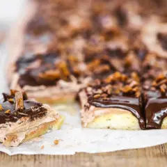 Mäktiga mjuka kakor i långpanna med chokladglasyr och krispiga bitar. En bit är uppskuren och visar lager av fluffig kräm.