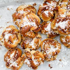 En hög med gyllene kanelbullar, toppade med pärlsocker. Perfekt för en fika, dessa sukat frukt-inspirerade bakverk doftar ljuvligt.