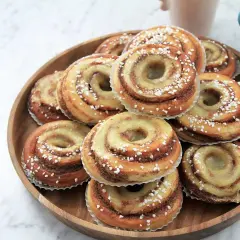 En hög med nybakade brioche bullar, glaserade och strösslade med pärlsocker, redo att avnjutas.