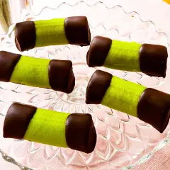 Fem gröna punschrullar med chokladtoppar på ett glasfat. Perfekt för ett enkelt punschrulle recept.