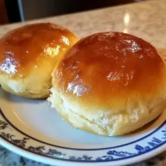 Två gyllene bullar med sylt på en tallrik. Perfekta för fika.