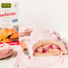 En saftig vegansk rulltårta med hallonfyllning och rosa glasyr. Bredvid står en förpackning med glutenfritt mjöl.