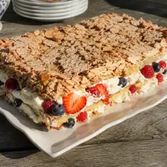 En härlig kladdkaka tårta med grädde och bär, toppad med mandel. Perfekt för sommaren!