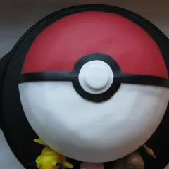 En fantastisk pokemon tårta formad som en pokéboll, med små pokemonfigurer som tittar fram.