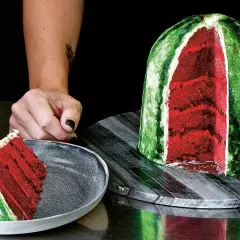 En skivad vattenmelon tårta med rött inre och grönt skal. En bit ligger på en tallrik.