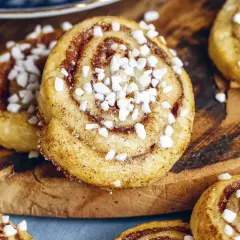 Nybakade kanelbulle kakor med pärlsocker på en träskärbräda. Perfekt fika!