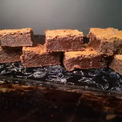 En hög med saftiga chokladbrownies på en glittrig svart bricka. Perfekt för en fika!