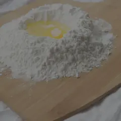 Mjöl och ett ägg på en skärbräda, redo att blandas. Kanske för en kaka där man använder bakpulver istället för jäst.