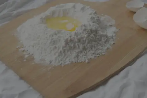 Mjöl och ett ägg på en skärbräda, redo att blandas. Kanske för en kaka där man använder bakpulver istället för jäst.