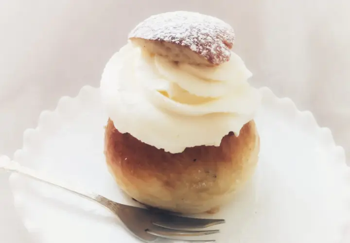 En semmeltårta med fluffig grädde och pudersocker, redo att avnjutas. Ett perfekt semmeltårta recept för fika.