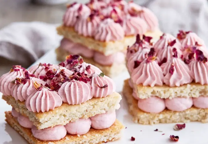 Delikata små mandelbotten tårtor med rosa grädde och torkade rosenblad. En dröm för ögat och gommen.