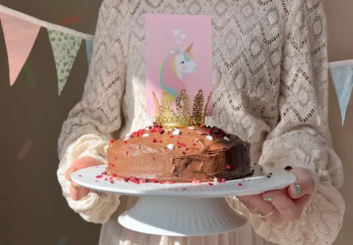 En chokladtårta med enhörningsdekoration och guldkrona, perfekt för roliga kakor barnkalas.