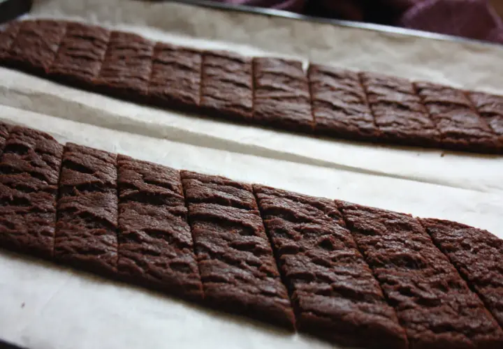Två långa rader med nybakade chokladsnittar på bakplåtspapper. Perfekt för ett chokladsnittar recept.
