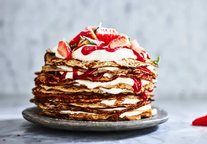 En imponerande pannkakstårta med grädde och jordgubbar, perfekt för ett somrigt pannkakstårta recept.