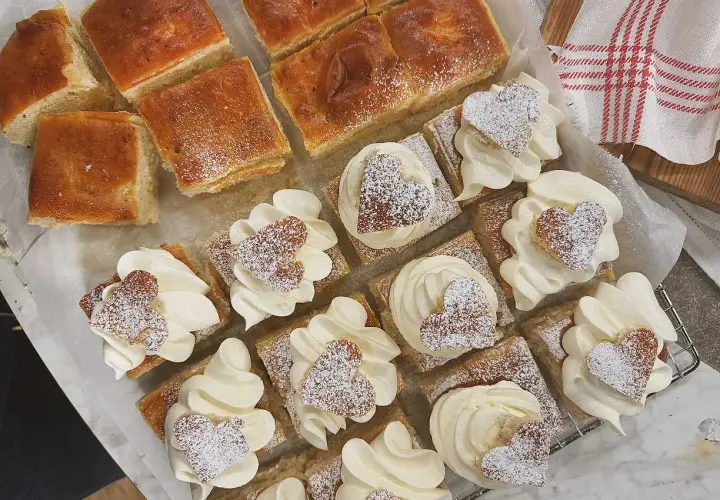 Fredriks fika: små fyrkantiga semlor med fluffig grädde och hjärtformade kakor, pudrade med florsocker. Perfekt för en mysig stund.