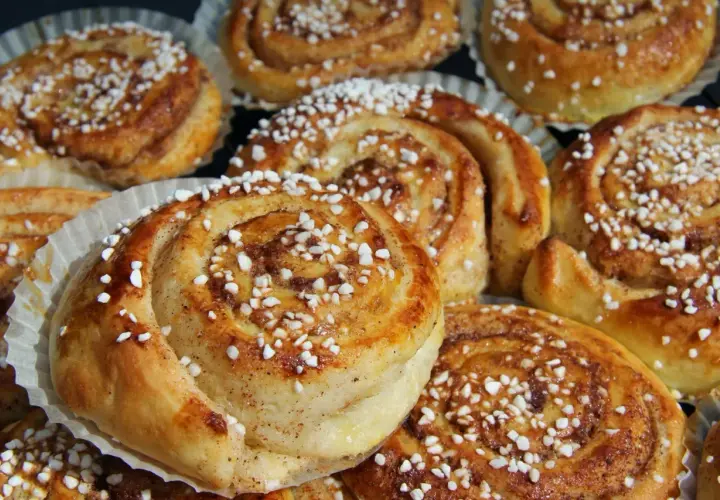 En tina med gyllene, nybakade kanelbullar toppade med pärlsocker. Perfekt för fika.