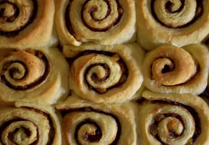 Nybakade kanelbullar med russin, redo att avnjutas. Doften av kanel sprider sig i köket.