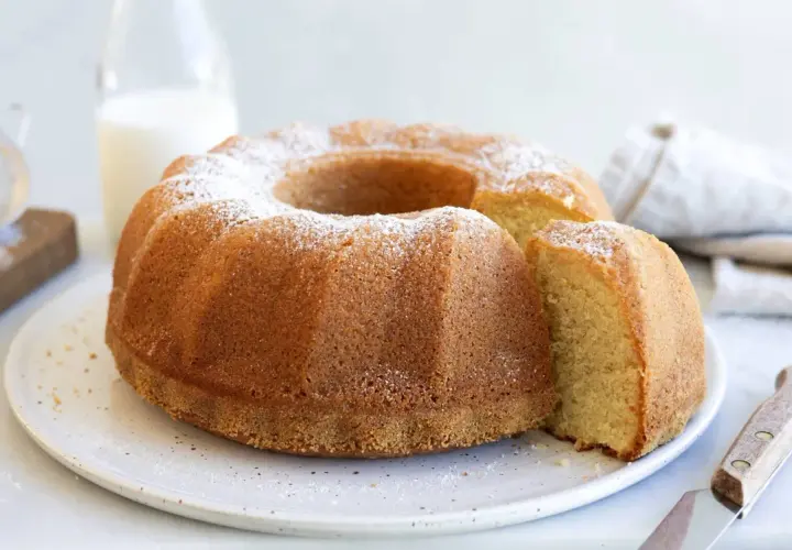 En gyllene sockerkaka med pudersocker, perfekt för ett enkelt sockerkaka recept. En bit är uppskuren.