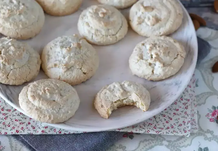 En tallrik med hembakade amaretti-kakor, perfekta för ditt nästa amaretti recept. En kaka är uppäten!