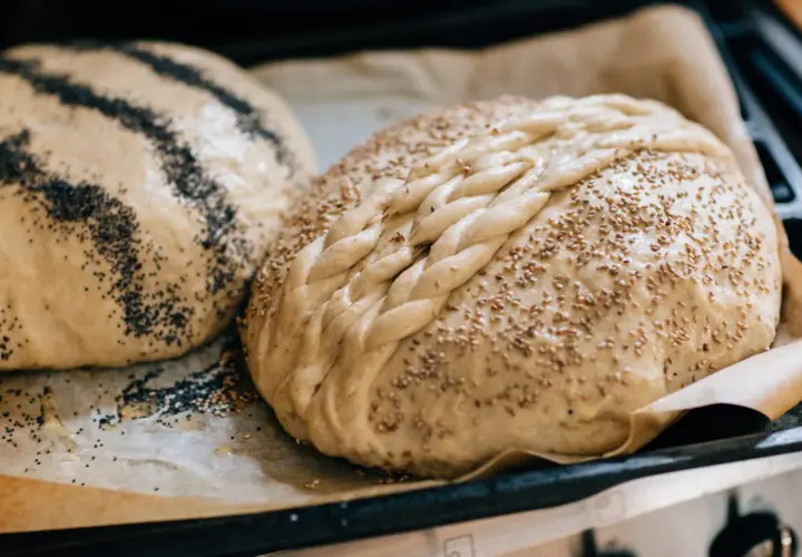 Två hembakade bröd, ett med vallmofrön och ett flätat med sesamfrön, redo att baka och frysa in.