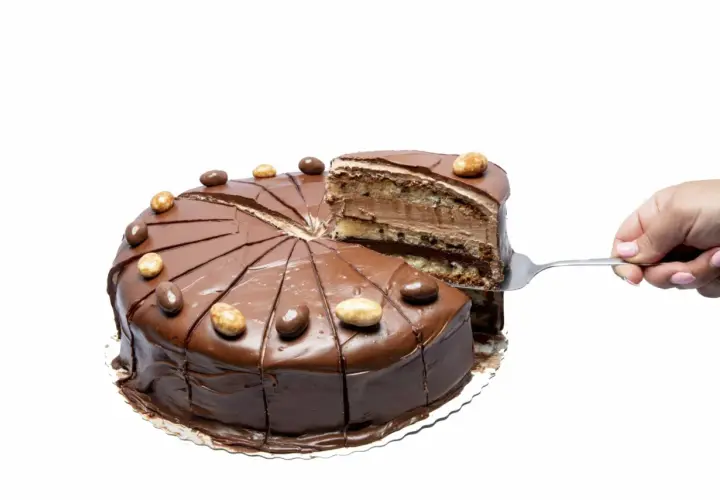 En chokladig nutellatårta med flera lager, en bit lyfts upp med en tårtspade. Perfekt för ett nutellatårta recept.