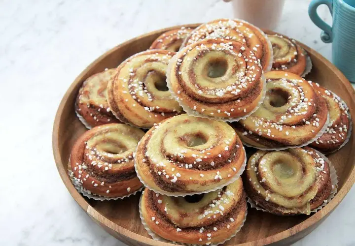 En hög med nybakade brioche bullar, glaserade och strösslade med pärlsocker, redo att avnjutas.