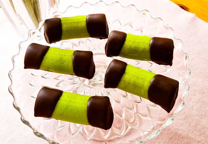 Fem gröna punschrullar med chokladtoppar på ett glasfat. Perfekt för ett enkelt punschrulle recept.