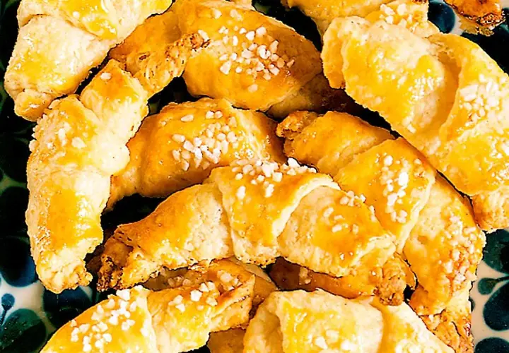 En hög med gyllene gifflar med mandelmassa, toppade med pärlsocker. Perfekta till fikat!