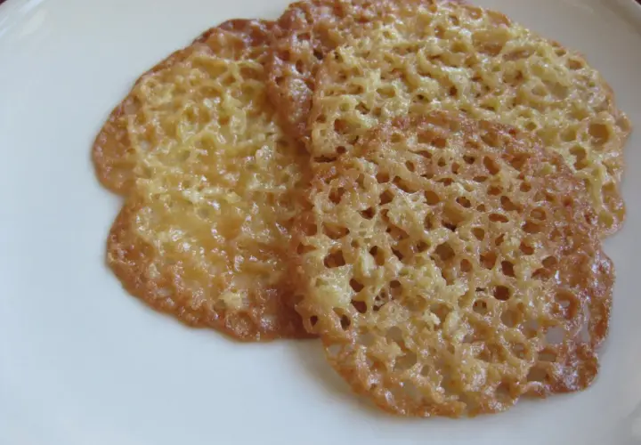 Tre gyllene, krispiga havreflarn ligger på en vit tallrik. Perfekta för ett enkelt recept på havreflarn.