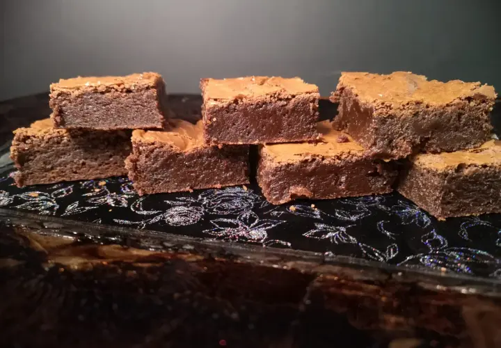 En hög med saftiga chokladbrownies på en glittrig svart bricka. Perfekt för en fika!