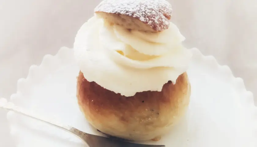 En semmeltårta med fluffig grädde och pudersocker, redo att avnjutas. Ett perfekt semmeltårta recept för fika.