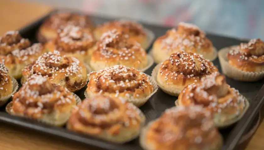 Nybakade glutenfria bullar med pärlsocker på en plåt, redo att avnjutas.