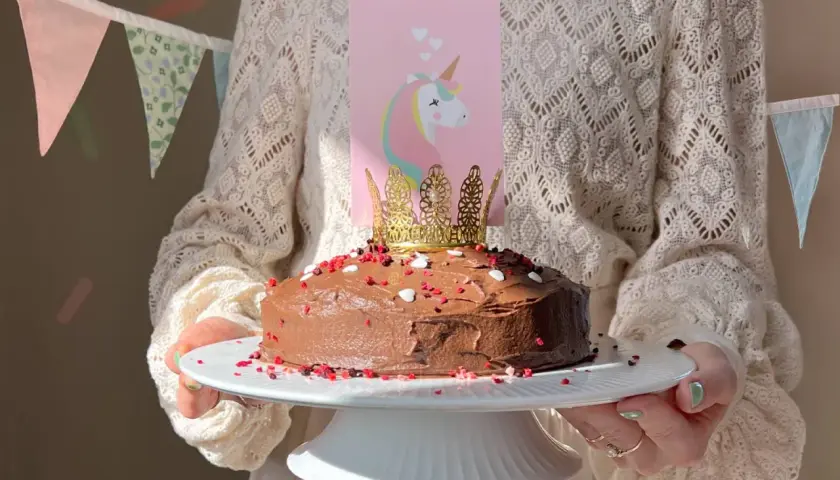 En chokladtårta med enhörningsdekoration och guldkrona, perfekt för roliga kakor barnkalas.