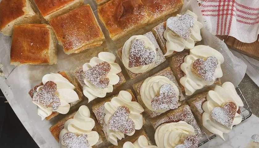 Fredriks fika: små fyrkantiga semlor med fluffig grädde och hjärtformade kakor, pudrade med florsocker. Perfekt för en mysig stund.