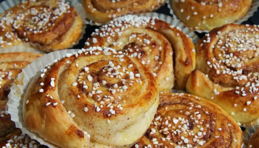 En tina med gyllene, nybakade kanelbullar toppade med pärlsocker. Perfekt för fika.