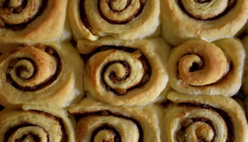 Nybakade kanelbullar med russin, redo att avnjutas. Doften av kanel sprider sig i köket.