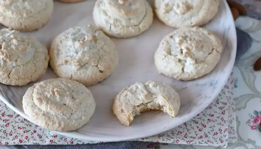En tallrik med hembakade amaretti-kakor, perfekta för ditt nästa amaretti recept. En kaka är uppäten!